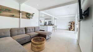 Een moderne woonkamer met een modulaire bank, een houten salontafel en een keuken op de achtergrond.