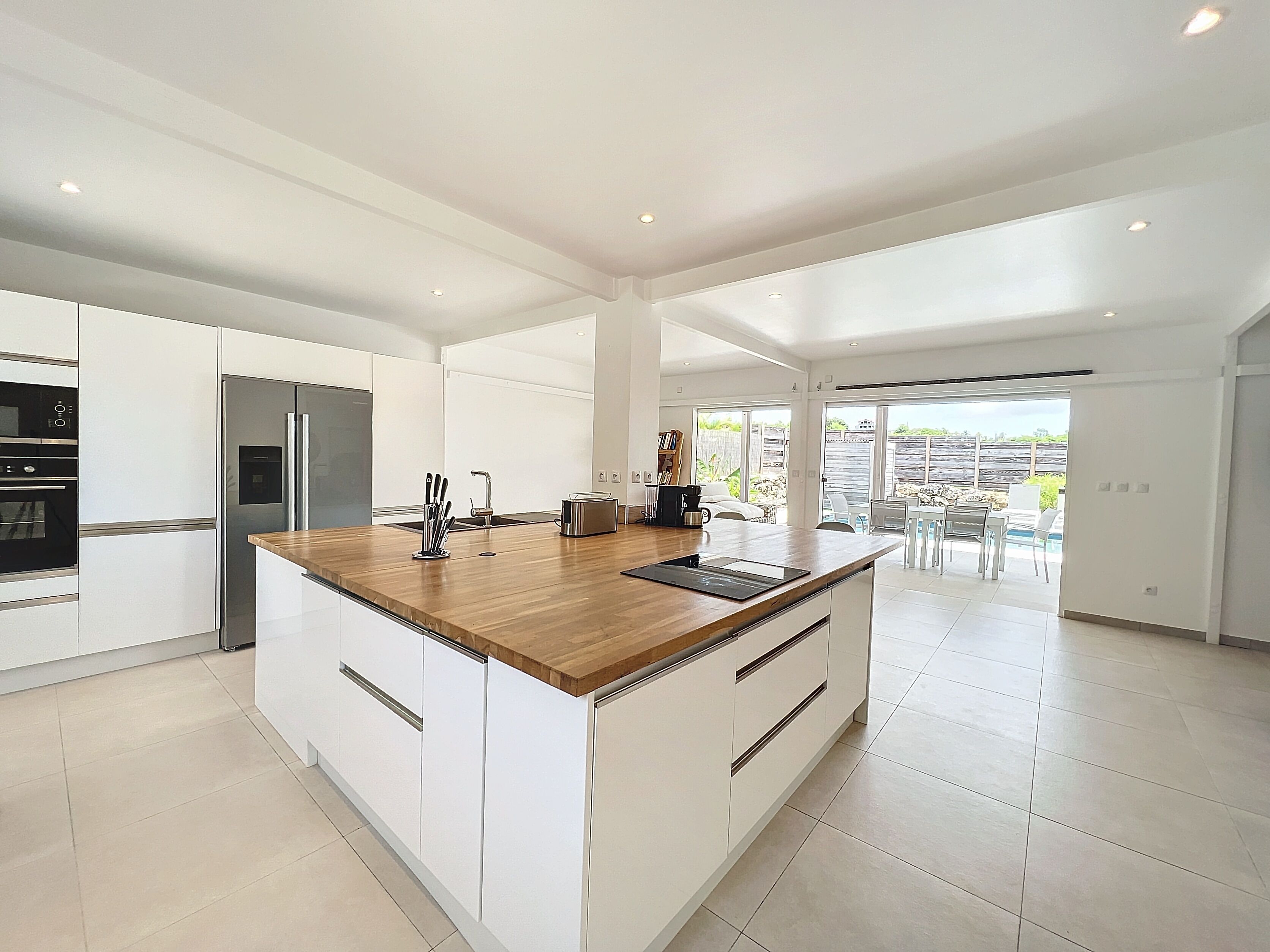 A modern kitchen with a wooden island, white cabinetry, and stainless steel appliances.