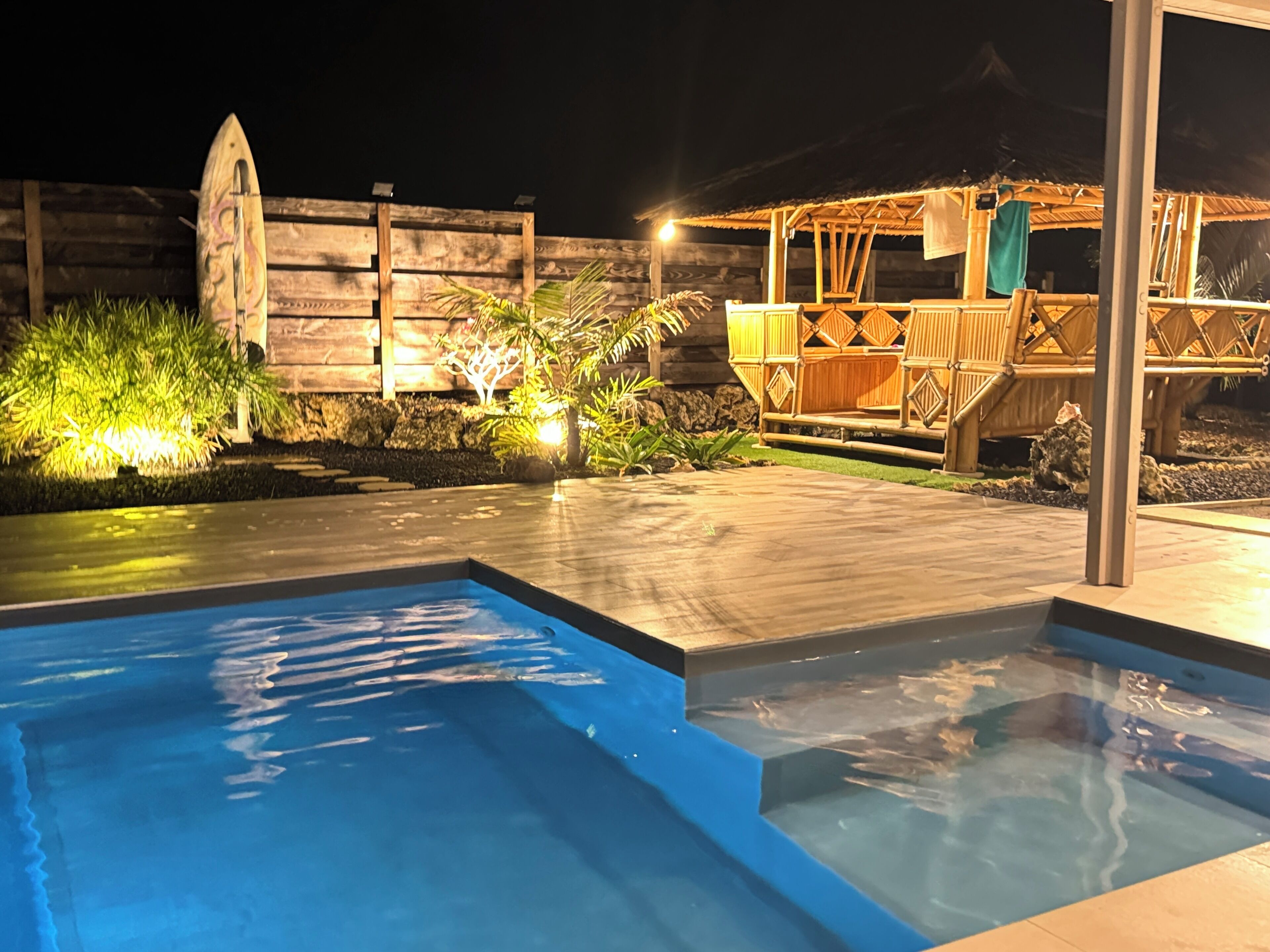 A swimming pool with a wooden deck and a wooden fence in the background.