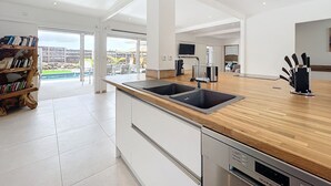Een moderne keuken met een houten aanrecht, roestvrijstalen apparatuur en uitzicht op de omgeving.