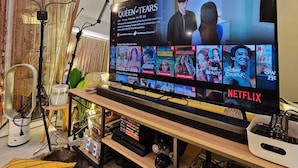 A modern living room with a large flat-screen TV displaying a Netflix interface, a decorative lamp, and a small table with a plant. - Azure Staycation by Siaos (Parañaque)