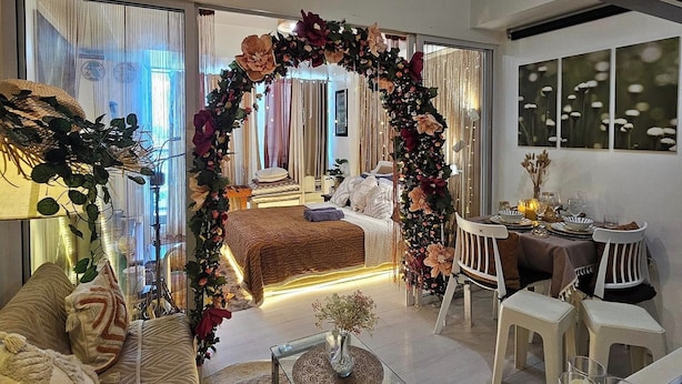 A modern living room with a sofa, coffee table, and a dining area with chairs and a table. - Azure Staycation by Siaos (Parañaque)