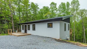 Ein modernes eingeschossiges Haus mit Kiesweg, Holzterrasse und einer kleinen Außentreppe.