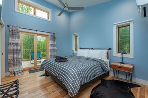 A bedroom with a bed, a ceiling fan, a window, and a view of the outdoors.