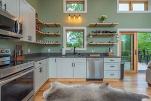 Una cocina moderna con electrodomésticos integrados, repisas de madera y vistas por una ventana.