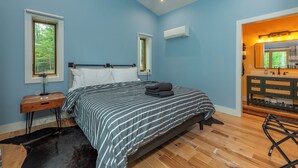 Ein Schlafzimmer mit Bett, Nachttisch, Kommode und Schminktisch mit Spiegel.