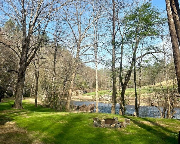 A natural landscape with trees, a grassy area, and a body of water.