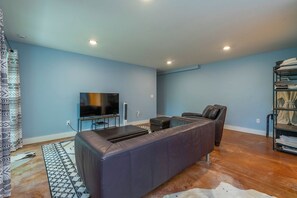 A modern living room with a leather sofa, a flat-screen TV, and a coffee table. - Mtn Retreat, River Access, Fire Pit, WiFi, Grill! (Spruce Pine)