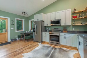 A modern kitchen with white cabinets, stainless steel appliances, and a wooden floor. - Mtn Retreat, River Access, Fire Pit, WiFi, Grill! (Spruce Pine)