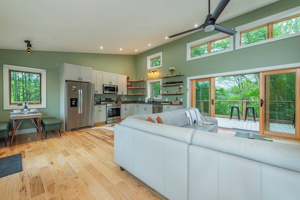Una cocina moderna con armarios blancos, un refrigerador y una zona de comedor con mesa y sillas.