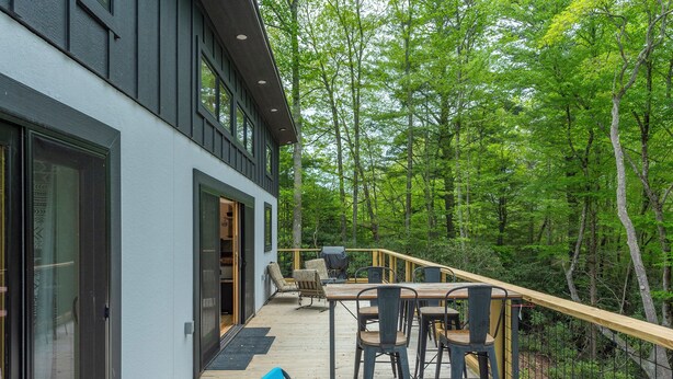 Ein modernes Haus mit Terrasse mit Blick auf einen Wald.