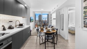 A modern kitchen with a dining area, large windows, and a city view.
