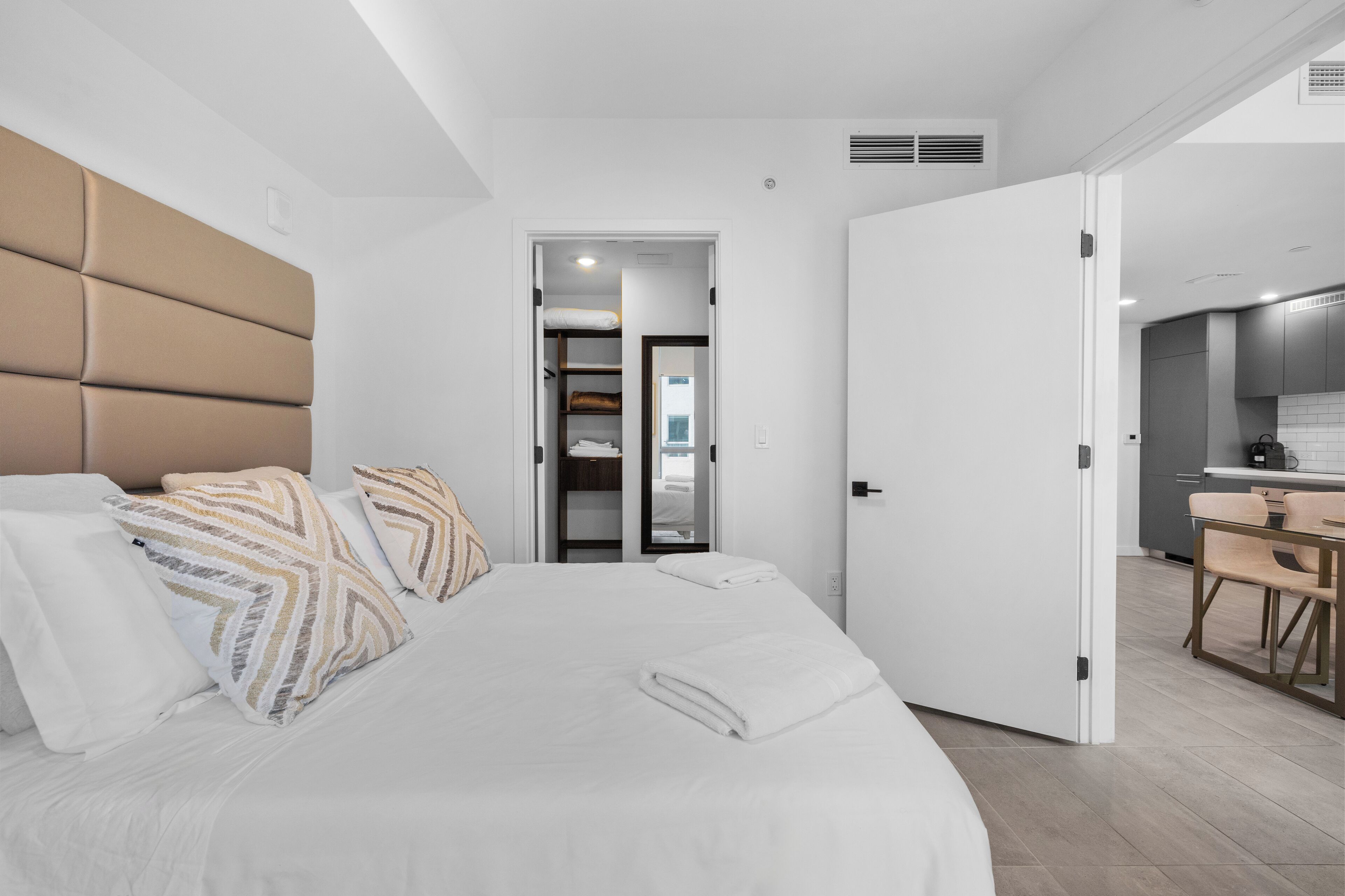 Een moderne slaapkamer met een groot bed, een vastgezet hoofdbord en een inloopkast.