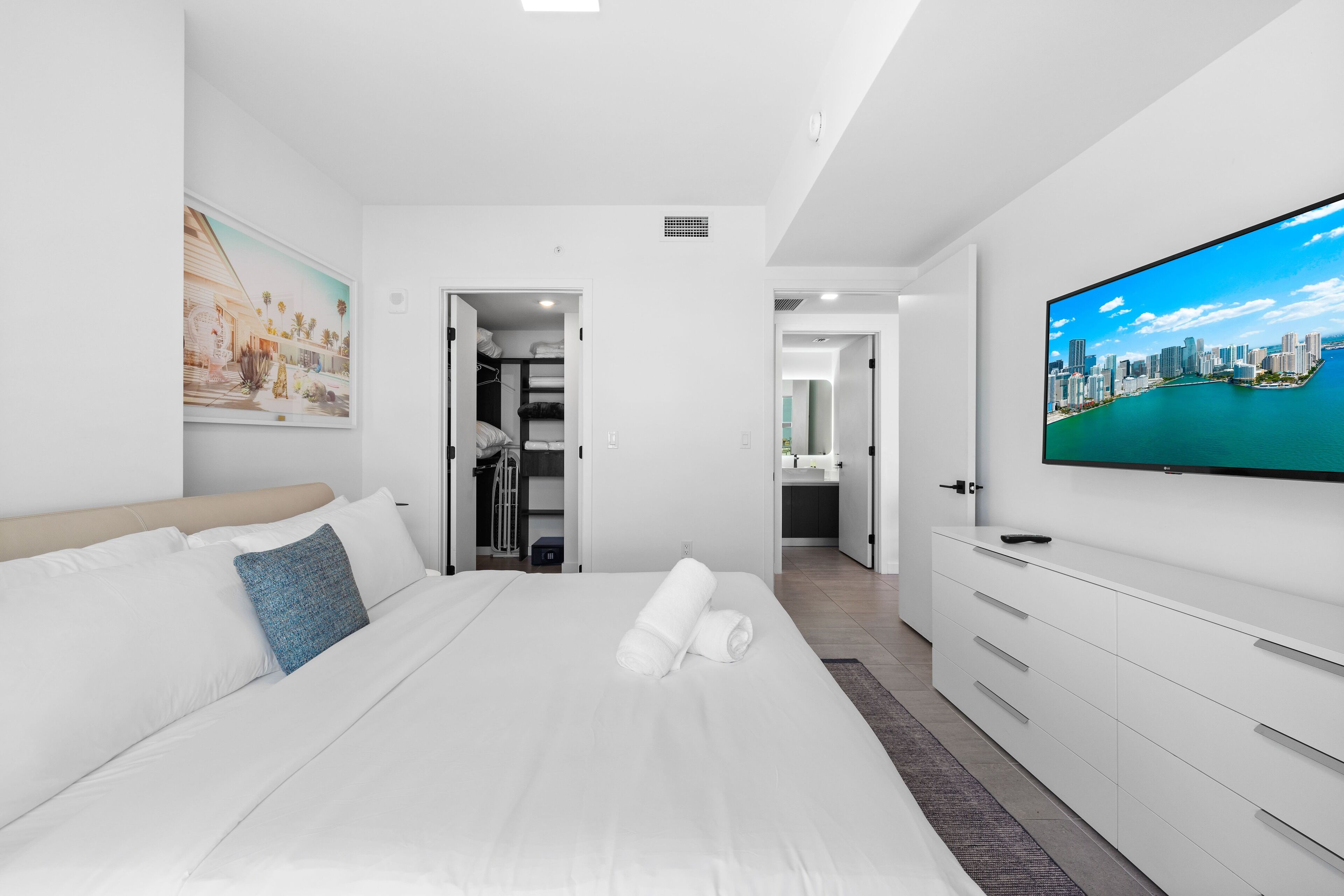 Una habitación de hotel moderna con una cama grande, un televisor en la pared y vistas a la ciudad.