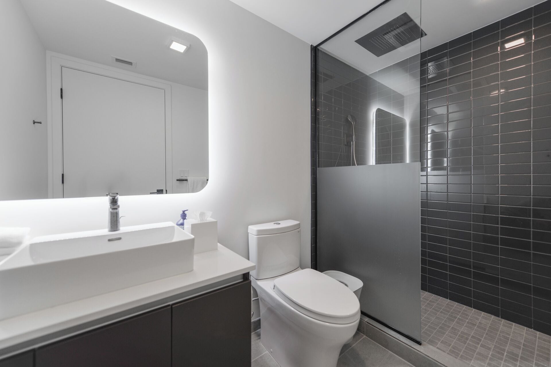 A modern bathroom with a white sink, mirror, and toilet.