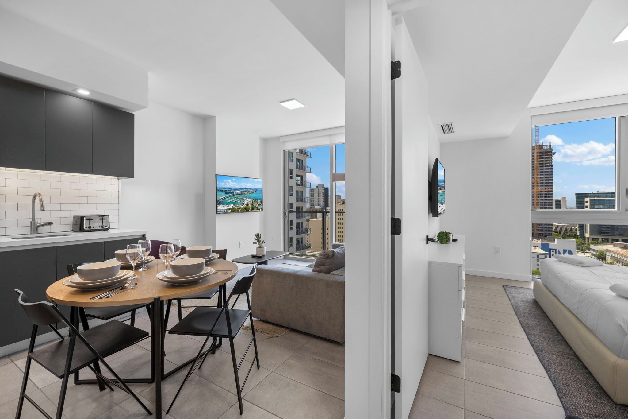 Eine moderne Wohnung mit Küche, Essbereich und einem Balkon mit Blick auf die Stadt.