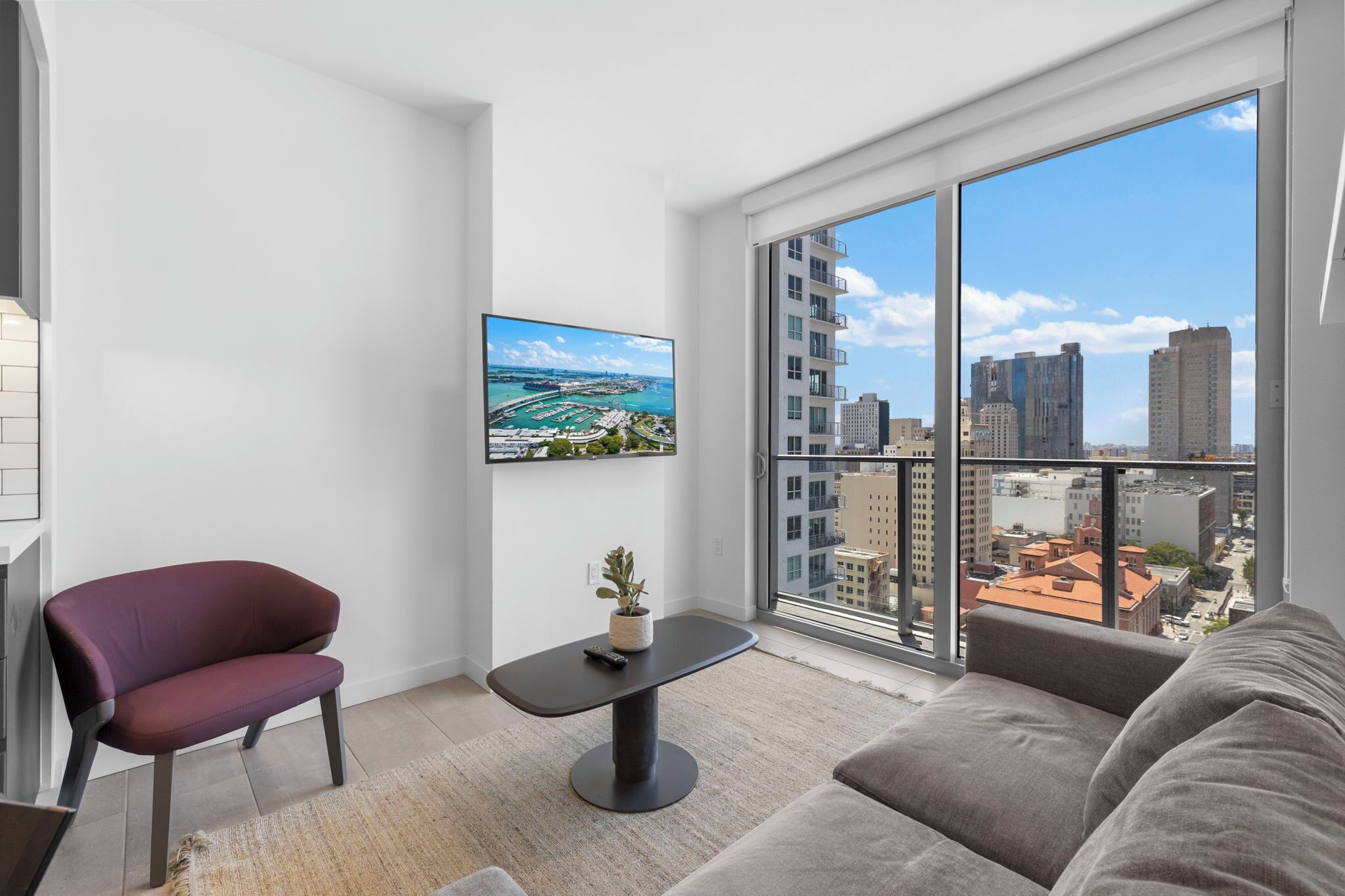 Una sala de estar moderna con un ventanal grande, un sofá, un sillón, una mesita y un cuadro en la pared.