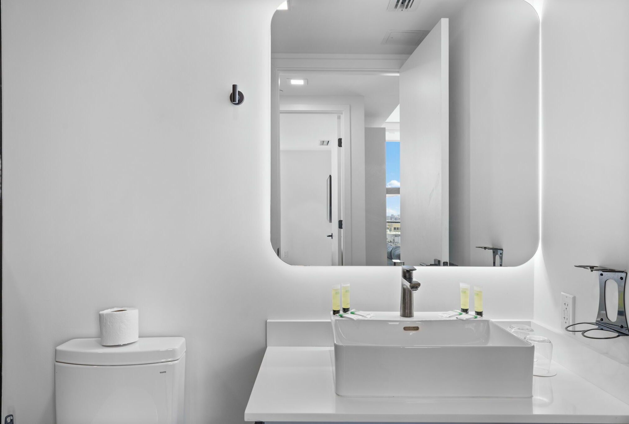 A modern bathroom with a white sink, mirror, and toilet.