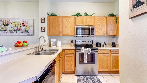 A modern kitchen with wooden cabinets, stainless steel appliances, and a fruit bowl.