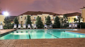 Une piscine avec des chaises longues et une terrasse en briques.