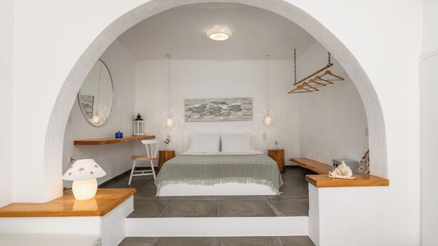 Een slaapkamer met een bed, een spiegel, een schilderij en een houten bank.