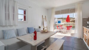 Een gezellige kamer met een houten tafel, een bank en uitzicht op zee.