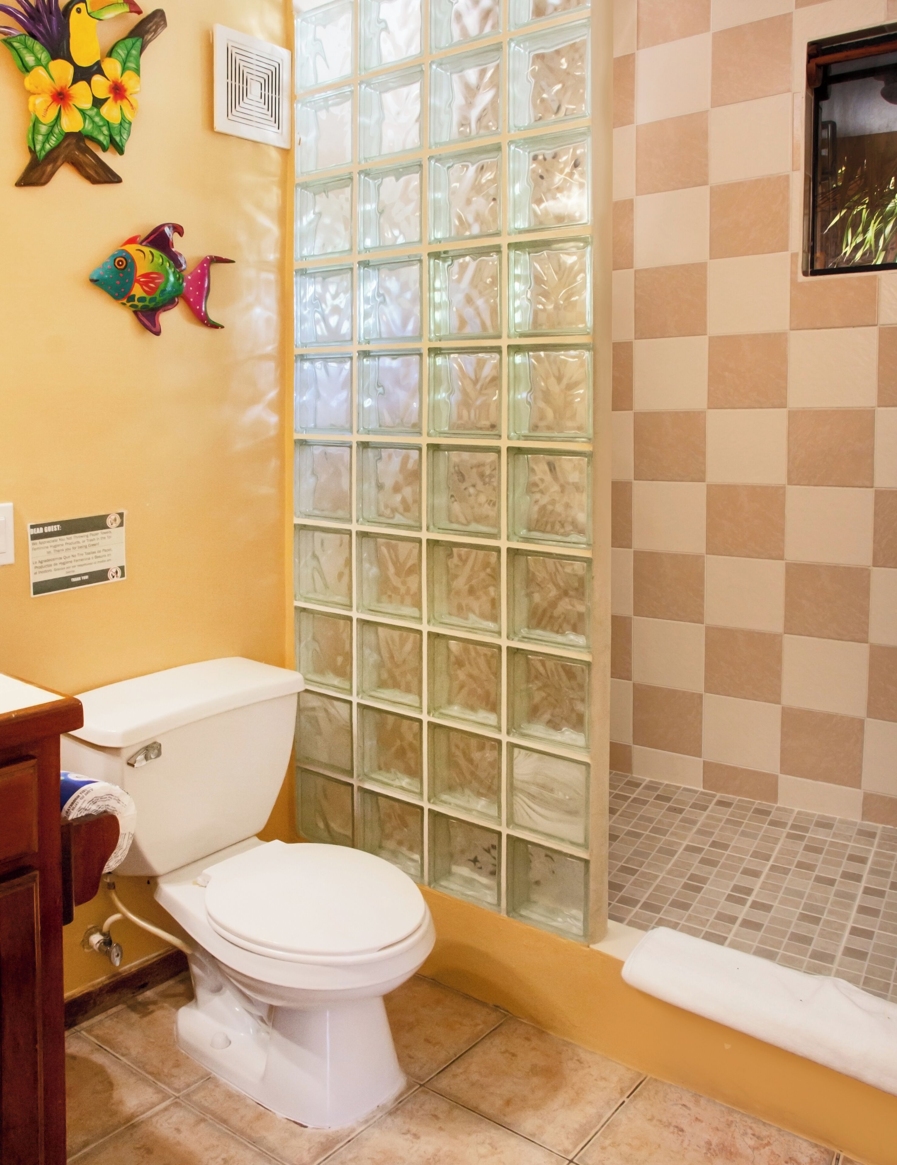 A bathroom with a toilet, a shower with a glass door, and decorative wall art.