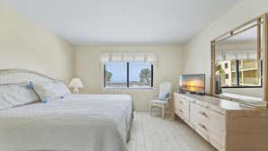 A bedroom with a bed, a TV, a dresser, and a window with blinds. - Oceanfront Balcony-Private Beach Access-Heated Pool (Cape Canaveral)