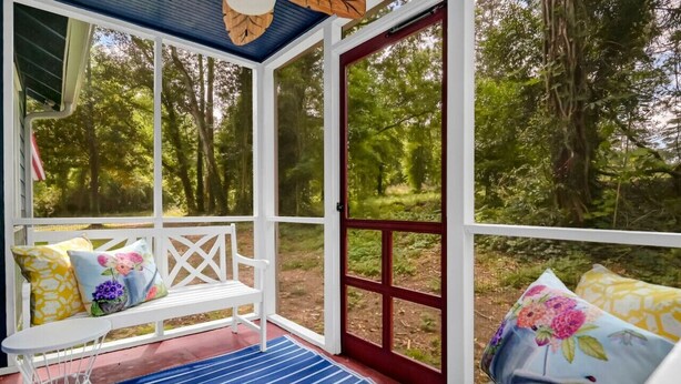 A covered porch with a white bench, blue striped rug, and floral cushions. - Blue Bungalow |  2BR 1BA | Lexington (Lexington)