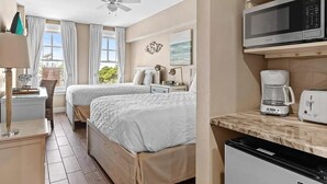 Een slaapkamer met twee bedden, een plafondventilator, een magnetron, een koffiezetapparaat en een vaatwasser.