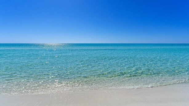 Een strand met helder turquoise water en een heldere lucht.