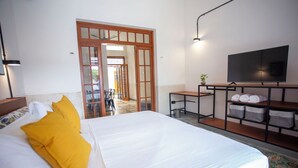 A hotel room with a large bed, a TV, a desk, and a view of the outside. - Casa Lluavi (Mérida)