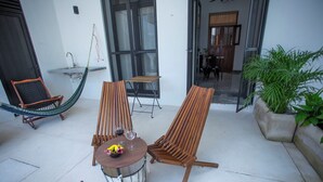 A patio with two wooden chairs, a small round table with a bowl and two wine glasses, and a hammock. - Casa Lluavi (Mérida)