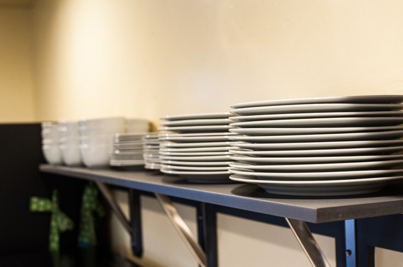 Uma fileira de pratos brancos empilhados sobre uma mesa de metal em uma cozinha.