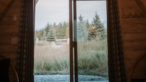 Eine Holzbalkendecke mit einer Pendelleuchte und einem Fenster mit Vorhängen.