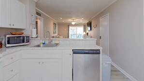 Een moderne keuken met witte kastjes, een magnetron, een vaatwasser en een spoelbak.