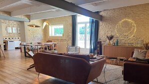 Ein geräumiges Wohnzimmer mit Holzboden, einem braunen Sofa und einem Essbereich mit Tisch und Stühlen.