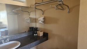 Une salle de bain équipée d’un lavabo, d’un miroir, d’un porte-serviettes et d’une machine à café.