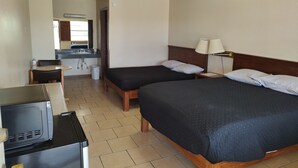 Une chambre d’hôtel avec deux lits, un bureau avec un ordinateur, un lavabo et un miroir.
