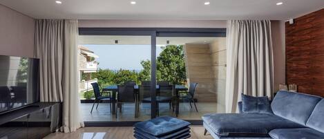 A modern living room with a sofa, TV, and a dining area with chairs and a table.