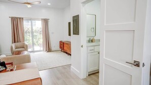 A modern room with a ceiling fan, a dining area with a table set, a sofa, and a wooden cabinet. - NEW LuxuryCondo Location Pool, BahaMar UNIT 5 (Nassau)