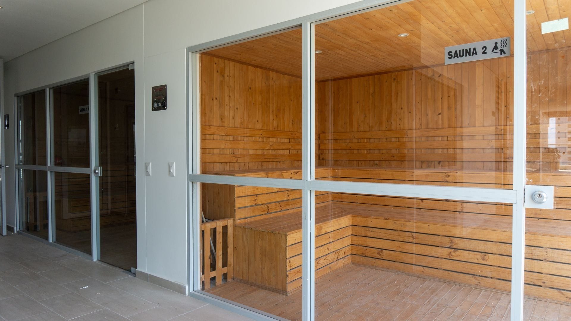 A sauna room with wooden walls and a glass door, labeled 'SAUNA 2'.