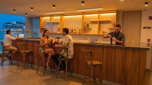 A bar area with wooden paneling, bar stools, and a bartender preparing drinks. - salguero suite 313 (Santa Marta)