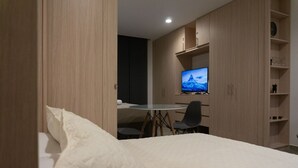 A hotel room with a bed, a round table with chairs, a television, and built-in wooden cabinets. - salguero suite 313 (Santa Marta)