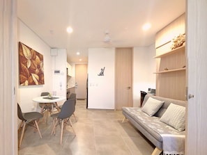 A modern living room with a sofa, dining table, and chairs. There is a kitchen area in the background. - salguero suite 313 (Santa Marta)