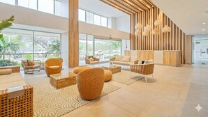 A spacious lobby with wicker furniture, large windows, and a modern wooden accent wall.