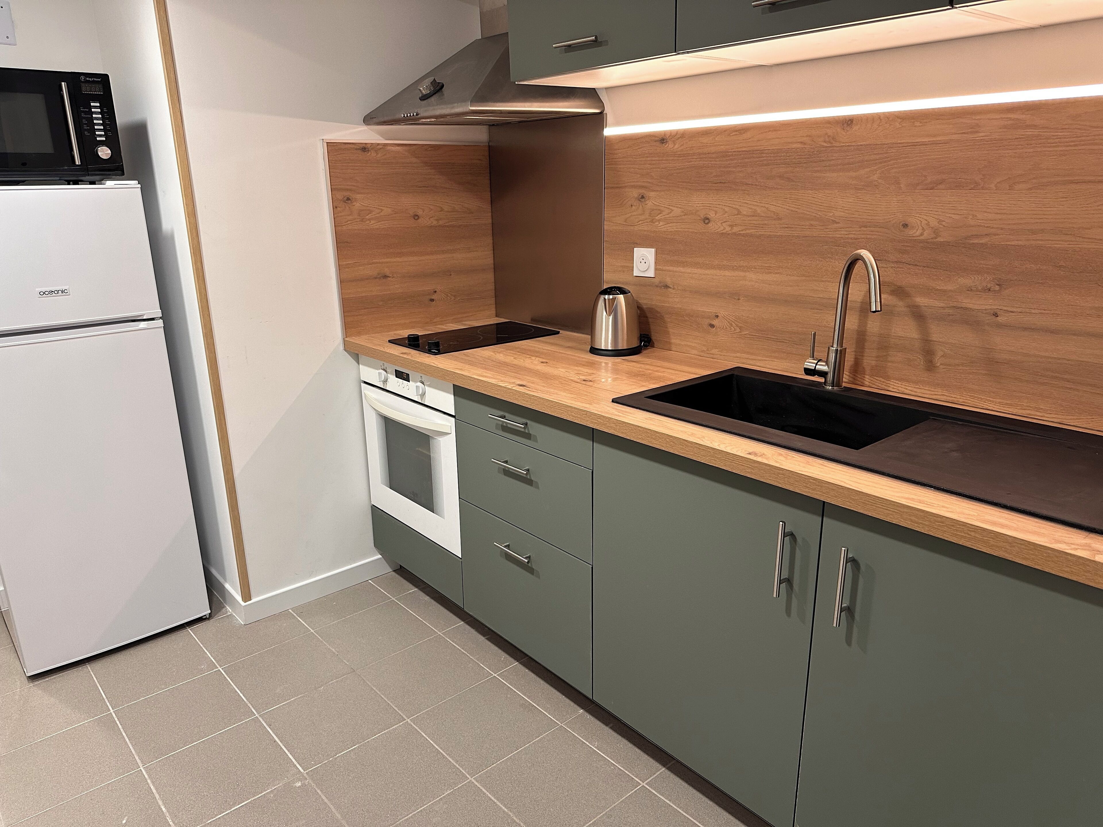 A kitchen with a built-in oven, a microwave, a sink, and wooden cabinets.