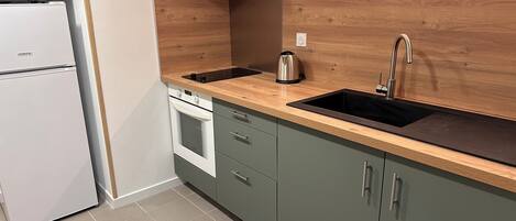 A kitchen with a built-in oven, a microwave, a sink, and wooden cabinets.
