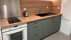 A modern kitchen with a stainless steel range hood, a built-in oven, a sink with a faucet, and wooden cabinetry.