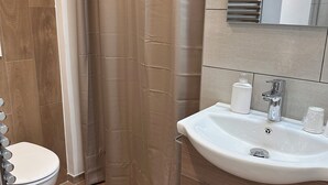 A modern bathroom with a white toilet, a sink with a mirror above it, and a shower curtain.